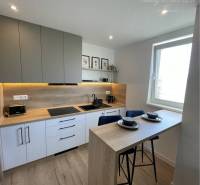 Vám ponúka na Prenájom 2-izbový byt s loggiou  - Kuchyňa v 2-izbovom byte s barovým pultom a podlahou s dreveným dekorom.