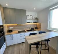 Vám ponúka na Prenájom 2-izbový byt s loggiou  - Kuchyňa v 2-izbovom byte s podlahou s dreveným dekorom a minimalistickým nábytkom.