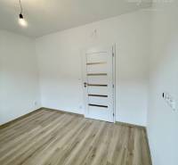 Vám ponúka modernú 4-izbovú novostavbu v Dunajs - Prázdna miestnosť s podlahou s dreveným dekorom v rodinnom dome s bielymi stenami.