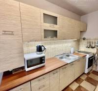 Vám ponúka 3-izbový byt s loggiou po kompletnej - Kuchyňa v 3-izbovom byte s podlahou s dreveným dekorom a mikrovlnkou na linke.