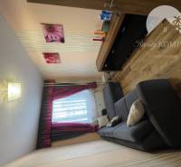 Vám ponúka 3-izbový byt s loggiou po kompletnej - Obývacia izba s podlahou s dreveným dekorom, pohovkou a dekoratívnymi obrazmi v 3-izbovom byte.