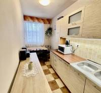 Vám ponúka 3-izbový byt s loggiou po kompletnej - Kuchyňa v 3-izbovom byte s podlahou s dreveným dekorom a šachovnicovým vzorom.