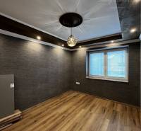 Vám ponúka na PREDAJ kompletne zrekonštruovaný  - Miestnosť rodinného domu s tmavou stenou, podlahou s dreveným dekorom a zaujímavým stropom.