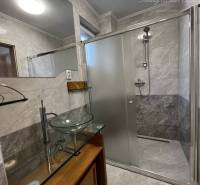 Vám ponúka na PREDAJ kompletne zrekonštruovaný  - Kúpeľňa v rodinnom dome s veľkým zrkadlom, skleným umývadlom a sprchovým kútom.