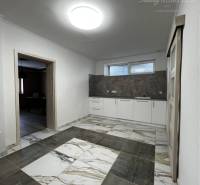 Vám ponúka na PREDAJ kompletne zrekonštruovaný  - Interiér rodinného domu s dlaždicovou podlahou, bielymi stenami a kuchynskou linkou.