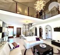 Ponúka na PREDAJ zrekonštruovaný 5 izbový podpi - Luxusná obývacia izba v rodinnom dome s dekoráciami a schodiskom na poschodie.