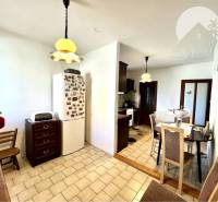 Ponúka na PREDAJ zrekonštruovaný 5 izbový podpi - Jedáleň v rodinnom dome s chladničkou, svetlami a stolom pre štyri osoby.