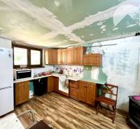 Ponúka na PREDAJ viničný domček s priestranným  - Kuchyňa v Chate s drevenou podlahou, chladničkou a hnedým nábytkom.