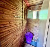 Ponúka na PREDAJ viničný domček s priestranným  - Chata s drevenými stenami a fialovým košom na prádlo.