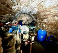 Ponúka na PREDAJ viničný domček s priestranným  - Klenbová pivnica na chate s uskladnenými nástrojmi a modrou nádobou.