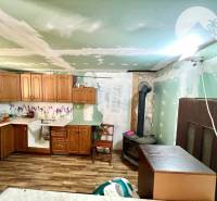 Ponúka na PREDAJ viničný domček s priestranným  - Kuchyňa v Chate s dreveným nábytkom, sporákom a laminátovou podlahou.