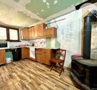 Ponúka na PREDAJ viničný domček s priestranným  - Kuchyňa v chate s drevenými skrinkami a pecou, vhodná pre pobyt v prírode.