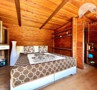 Ponúka na PREDAJ viničný domček s priestranným  - Drevený interiér chaty s posteľou a skriňou v útulnom priestore.