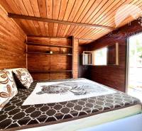 Ponúka na PREDAJ viničný domček s priestranným  - Drevený interiér chaty s posteľou a oknom.