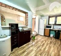 Ponúka na PREDAJ viničný domček s priestranným  - Kuchyňa v Chate so spotrebičmi, dreveným nábytkom a dlažbou na podlahe.