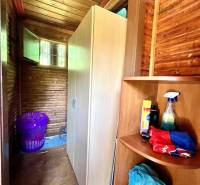 Ponúka na PREDAJ viničný domček s priestranným  - Drevený interiér s policami a prádlovým košom v chate.