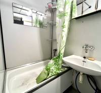 Ponúka na PREDAJ 1 izbový byt v Komárne - Kúpeľňa v 1-izbovom byte s vaňou, sprchovým závesom a umývadlom.