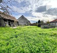 Vám ponúka na PREDAJ pozemok so starším rodinný - Pozemky - bývanie v Orechovej Potôni so starými budovami a zelenou trávou.