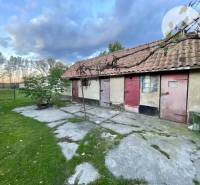 Investičný pozemok s obývateľným domom vo Vrakúni - Rodinný dom vo Vrakúni s vedľajšou budovou a trávnatým pozemkom, obloha s oblakmi.