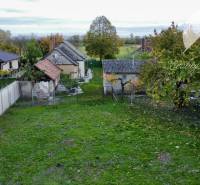 Investičný pozemok s obývateľným domom vo Vrakúni - Záhrada a starší dom v Vrakúni s oplotením a stromami v pozadí.