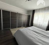 Vám ponuka na predaj útulný 3-izbový rodinný d - Spálňa v rodinnom dome s tmavou podlahou s dreveným dekorom a veľkou skriňou.