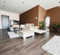 Vám ponuka na predaj útulný 3-izbový rodinný d - Obývacia izba v rodinnom dome s podlahou s dreveným dekorom a hnedými stenami.