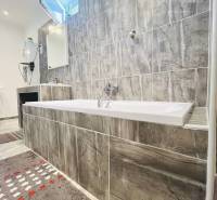 Vám ponuka na predaj útulný 3-izbový rodinný d - Kúpeľňa v rodinnom dome s vaňou a šedým obkladom.