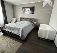 Vám ponuka na predaj útulný 3-izbový rodinný d - Spálňa v rodinnom dome s podlahou s dreveným dekorom a béžovým kobercom.