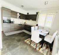 Vám ponuka na predaj útulný 3-izbový rodinný d - Kuchyňa v rodinnom dome s podlahou s dreveným dekorom a jedálenským stolom.