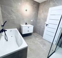 Vám ponúka na predaj moderný 4-izbový bungalov - Kúpeľňa s vaňou a sprchovacím kútom v rodinnom dome, dlažba s jemným vzorom.