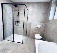 Vám ponúka na predaj moderný 4-izbový bungalov - Kúpeľňa rodinného domu s veľkoformátovými dlaždicami, sprchovacím kútom a vaňou.