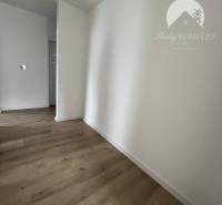 Vám ponúka na predaj moderný 4-izbový bungalov - Interiér rodinného domu s podlahou s dreveným dekorom a bielymi stenami.