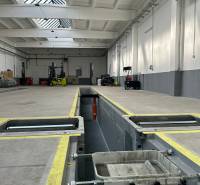 Autoservis s výbavou pre vozidlá v uzavretom priemyselnom areáli - HC - Priemyselný priestor s nabíjacou stanicou, technikou a svetlíkom v budove.