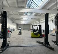 Autoservis s výbavou pre vozidlá v uzavretom priemyselnom areáli - HC - Interiér budovy s vysokozdvižným vozíkom a automechanickou technikou.