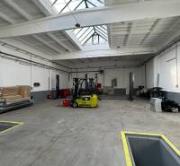 Autoservis s výbavou pre vozidlá v uzavretom priemyselnom areáli - HC - Priemyselný interiér budovy s presvetlenou strechou a žltým vysokozdvižným vozíkom.