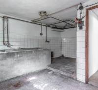 I Na predaj dvojposchodový 5i rodinný dom pri Žiline - Suterén rodinného domu s šedým umývadlom, bielymi obkladačkami a betónovou podlahou.