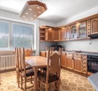 I Na predaj dvojposchodový 5i rodinný dom pri Žiline - Kuchyňa v rodinnom dome s drevenými skrinkami a jedálenským stolom, podlaha s dekorom.