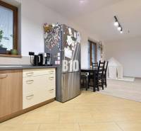 Veľkometrážny 3 izbový byt s garážou - Kuchyňa v 3-izbovom byte s dreveným dekorom podlahy a jedálenským stolom.