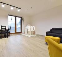 Veľkometrážny 3 izbový byt s garážou - Obývačka v 3-izbovom byte s podlahou s dreveným dekorom a žltým kreslom.