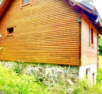 Rekreačná chata – Banská Štiavnica, časť Štefultov - Drevený rodinný dom v Štefultove s kamennou základňou obklopený zeleňou.
