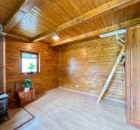 Rekreačná chata – Banská Štiavnica, časť Štefultov - Interiér chaty s drevenými prvkami, pieckou a podlahou s dreveným dekorom.