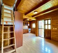 Rekreačná chata – Banská Štiavnica, časť Štefultov - Interiér rodinného domu s drevenými stenami, podlahou, kuchynskou linkou a schodmi na poschodie.