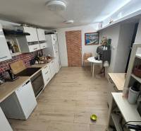 4 izbová celoročná chata v Kučišdorfskej doline na predaj - Kuchyňa v chate s podlahou s dreveným dekorom, svetlými skrinkami a jedálenským stolom.