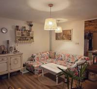 MH283 – Na predaj krásny rodinný dom vo vidieckom štýle - Rodinný dom, útulná obývačka, kvetinový gauč, dekoračné police, podlaha s dreveným dekorom.