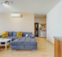 4i byt s terasou a parkovaním v tichej časti Rovinky | 89m2 - Obývacia izba v 4-izbovom byte s podlahou s dreveným dekorom a veľkou sedačkou.