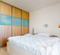 4i byt s terasou a parkovaním v tichej časti Rovinky | 89m2 - Spálňa v 4-izbovom byte s posteľou a veľkou vstavanou skriňou, podlaha s dreveným dekorom.