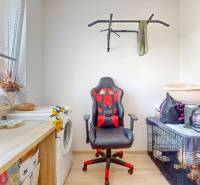 4i byt s terasou a parkovaním v tichej časti Rovinky | 89m2 - Izba s pracovnou stoličkou, cvičebným zariadením a dreveným dekorom v 4-izbovom byte.