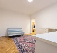 Slnečný 3-izbový byt, Kramáre - Izba v 3-izbovom byte s pohovkou, orientálnym kobercom a podlahou s dreveným dekorom.