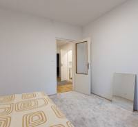 Slnečný 3-izbový byt, Kramáre - Biela izba s otvorenými dverami, koberec, zrkadlo a posteľná prikrývka v 3-izbovom byte.