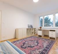 Slnečný 3-izbový byt, Kramáre - Spálňa v 3-izbovom byte s písacím stolom, kobercom a podlahou s dreveným dekorom.